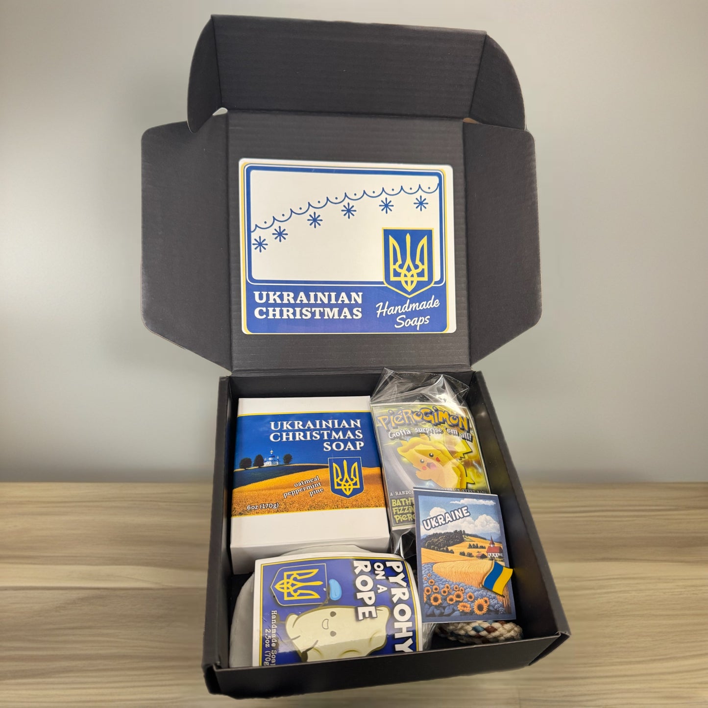 Box of Ukrainian Christmas handmade soaps with decorative packaging on a wooden surface.