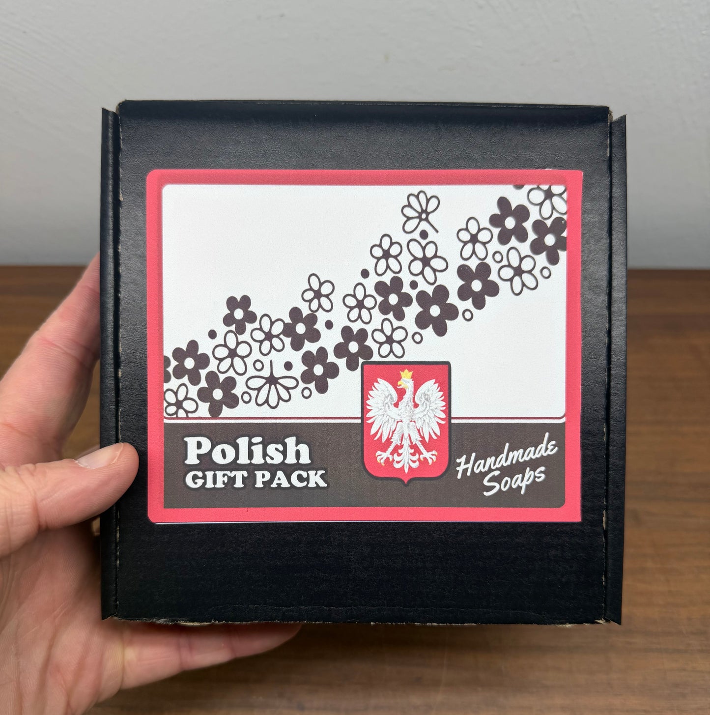 Handmade Soaps packaging with floral design and 'Polish Gift Pack' text held by a hand.